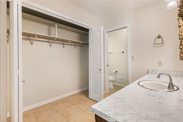 64 Rebie Way, Oroville, CA 95966 - bathroom featuring a sink, toilet, tile patterned floors, a walk in closet, and baseboards