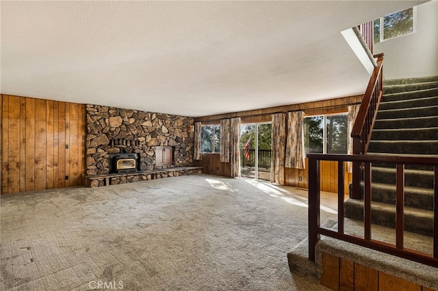 64 Rebie Way, Oroville, CA 95966 - unfurnished living room with wood walls, stairway, a fireplace, a textured ceiling, and carpet