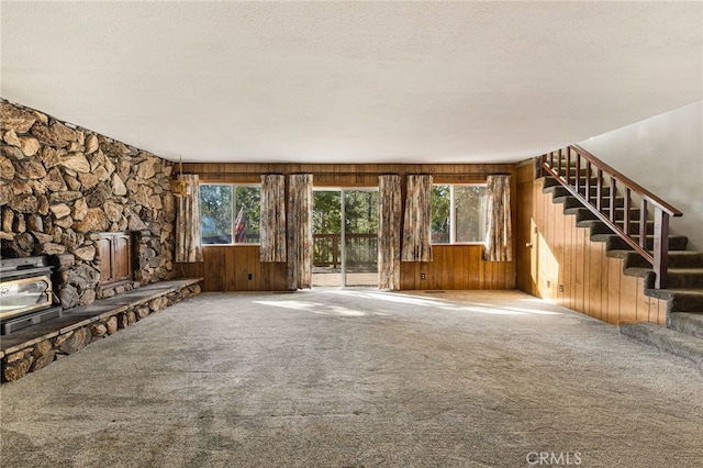 64 Rebie Way, Oroville, CA 95966 - unfurnished living room with carpet, stairway, plenty of natural light, wooden walls, and a textured ceiling