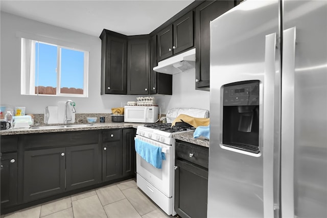 1665 E 84th St, Los Angeles, CA 90001 - kitchen with white appliances, under cabinet range hood, a sink, light stone counters, and dark cabinetry