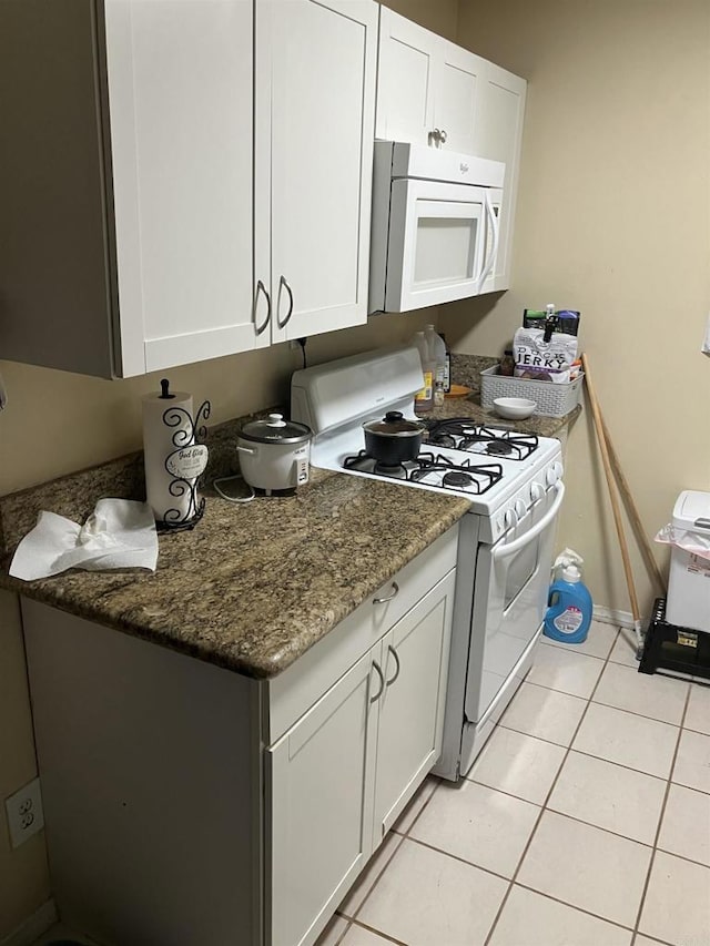 386771 Menlo Ave, San Diego, CA 92105 - kitchen featuring white appliances, white cabinetry, light tile patterned flooring, and dark stone counters