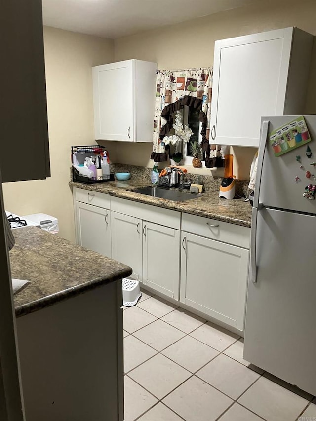 386771 Menlo Ave, San Diego, CA 92105 - kitchen with freestanding refrigerator, a sink, light tile patterned floors, and white cabinetry