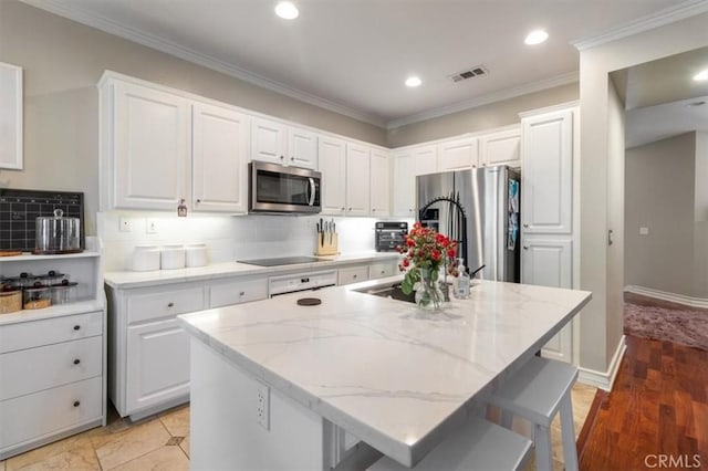 23402 Brookdale Ln Unit 56, Valencia, CA 91355 - kitchen with stainless steel appliances, white cabinets, light stone countertops, a center island, and recessed lighting