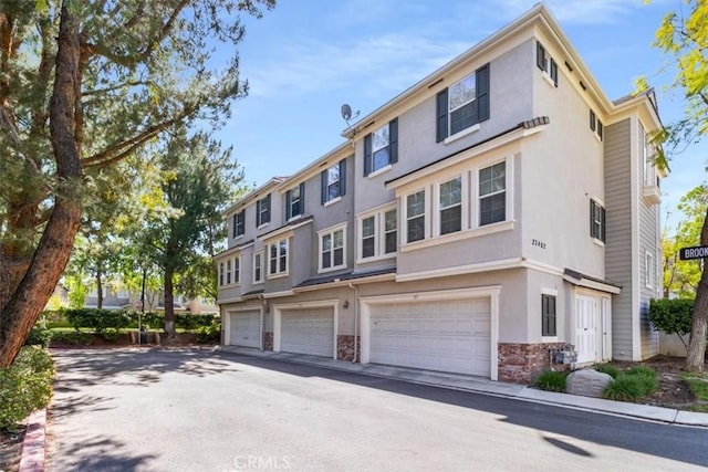 23402 Brookdale Ln Unit 56, Valencia, CA 91355 - view of property featuring stucco siding, a garage, and driveway