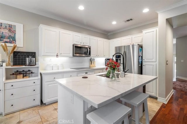 23402 Brookdale Ln Unit 56, Valencia, CA 91355 - kitchen with appliances with stainless steel finishes, a kitchen island, white cabinets, light stone counters, and decorative backsplash
