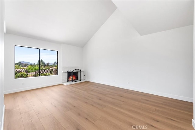 659 Valley Oak Ln, Newbury Park, CA 91320 - unfurnished living room with lofted ceiling, a lit fireplace, light wood-style flooring, and baseboards