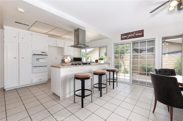 4950 Via Campeche, Riverside, CA 92507 - kitchen with oven, a warming drawer, island exhaust hood, and light tile patterned flooring