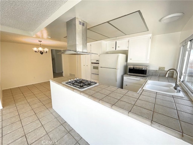 4950 Via Campeche, Riverside, CA 92507 - kitchen featuring white appliances, island range hood, a sink, a peninsula, and tile countertops
