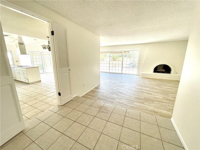 4950 Via Campeche, Riverside, CA 92507 - unfurnished living room with a textured ceiling, plenty of natural light, a fireplace with raised hearth, light tile patterned flooring, and baseboards