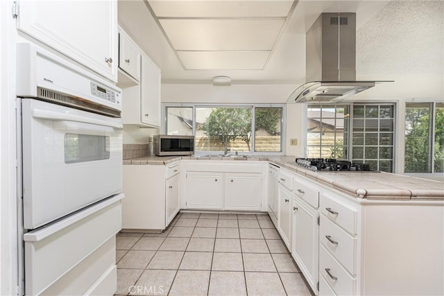 4950 Via Campeche, Riverside, CA 92507 - kitchen featuring island range hood, appliances with stainless steel finishes, a sink, light tile patterned floors, and a warming drawer