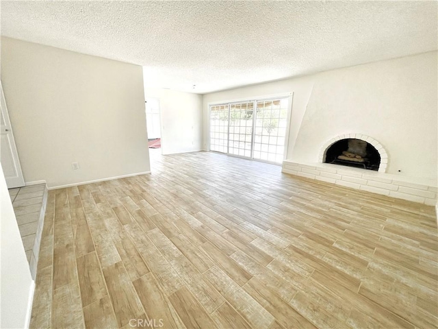 4950 Via Campeche, Riverside, CA 92507 - unfurnished living room with light wood finished floors, a brick fireplace, and a textured ceiling