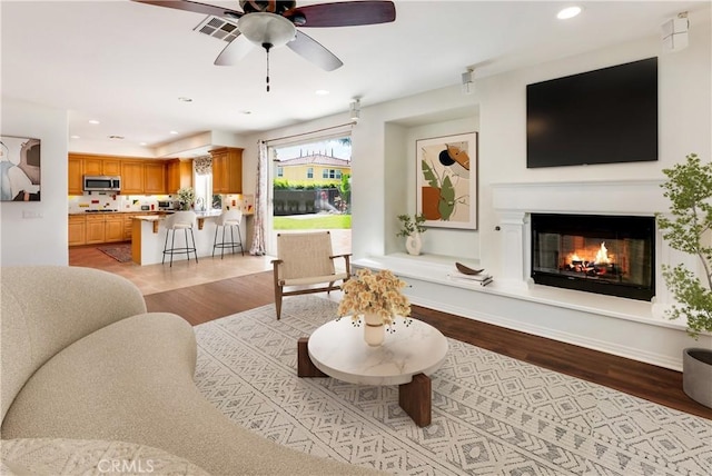 7659 Balasiano Ave, West Hills, CA 91304 - living area featuring light wood finished floors, a ceiling fan, recessed lighting, and a glass covered fireplace