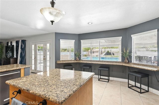 25 Del Brienza, Lake Elsinore, CA 92532 - kitchen with stainless steel dishwasher, a kitchen island, light stone countertops, light tile patterned floors, and brown cabinetry