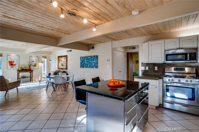 576 E Desert Holly Cir, Palm Springs, CA 92262 - kitchen featuring stainless steel appliances, light tile patterned flooring, backsplash, white cabinets, and wooden ceiling with exposed beams