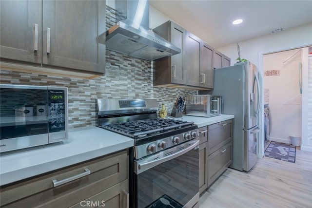 16732 Lassen St, Northridge, CA 91343 - kitchen with appliances with stainless steel finishes, wall chimney range hood, washing machine and dryer, backsplash, and light countertops
