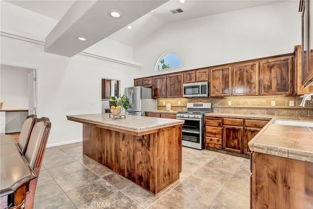 300 S Lombardi St, Porterville, CA 93257 - kitchen featuring appliances with stainless steel finishes, a sink, a center island, tasteful backsplash, and high vaulted ceiling