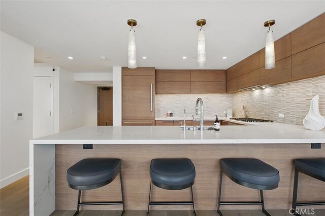 888 W E St Unit 505, San Diego, CA 92101 - kitchen with brown cabinets, a sink, light countertops, a peninsula, and recessed lighting