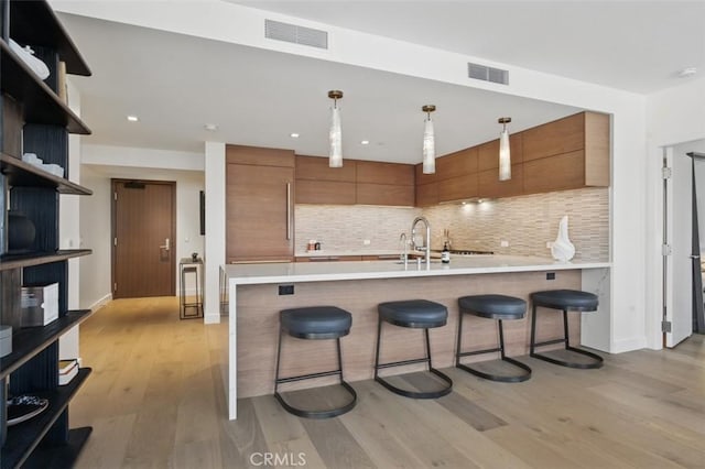 888 W E St Unit 505, San Diego, CA 92101 - kitchen featuring brown cabinetry, modern cabinets, a sink, a kitchen bar, and recessed lighting