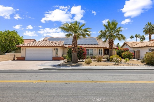 43300 Warner Trl, Palm Desert, CA 92211 - view of front of house featuring an attached garage, driveway, roof mounted solar panels, stucco siding, and a tile roof