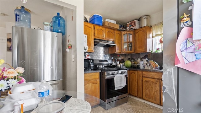 413 E 81st St, Los Angeles, CA 90003 - kitchen featuring appliances with stainless steel finishes, under cabinet range hood, brown cabinets, tasteful backsplash, and glass insert cabinets