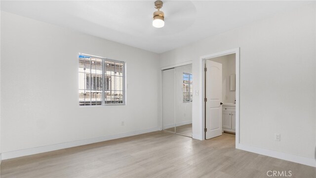 413 E 81st St, Los Angeles, CA 90003 - unfurnished bedroom featuring multiple windows, light wood finished floors, a closet, and baseboards