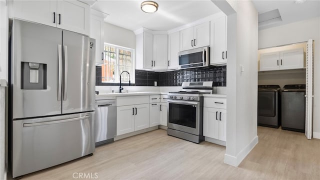 413 E 81st St, Los Angeles, CA 90003 - kitchen with stainless steel appliances, washing machine and clothes dryer, a sink, light wood finished floors, and light countertops
