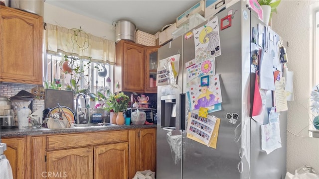 413 E 81st St, Los Angeles, CA 90003 - kitchen with stainless steel refrigerator with ice dispenser, a sink, brown cabinets, decorative backsplash, and a textured wall