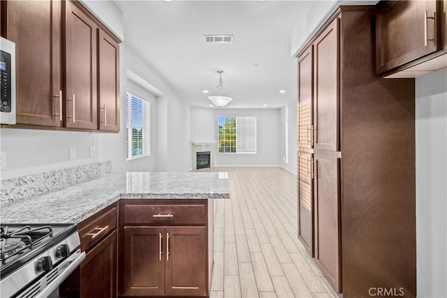 4615 Alekona Ct, Cypress, CA 90630 - kitchen with stainless steel range with gas cooktop, recessed lighting, a glass covered fireplace, a peninsula, and light wood-type flooring