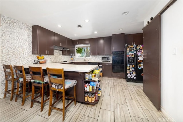 22892 Palm Ave, Grand Terrace, CA 92313 - kitchen with a peninsula, black appliances, under cabinet range hood, light countertops, and decorative backsplash