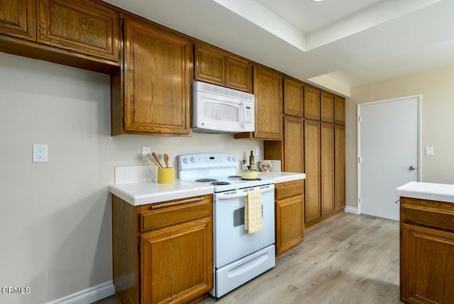 41019 Village 41, Camarillo, CA 93012 - kitchen with white appliances, brown cabinetry, light wood finished floors, and tile counters
