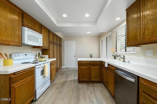 41019 Village 41, Camarillo, CA 93012 - kitchen featuring white appliances, a tray ceiling, light wood-style flooring, a sink, and a peninsula