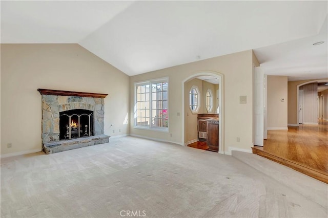 19371 Woodlands Dr, Huntington Beach, CA 92648 - unfurnished living room with vaulted ceiling, a fireplace, carpet flooring, baseboards, and arched walkways