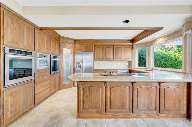 19371 Woodlands Dr, Huntington Beach, CA 92648 - kitchen with built in fridge, a sink, a peninsula, tasteful backsplash, and light stone countertops