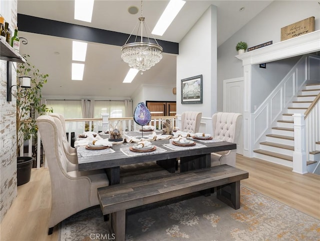 3504 Hightide Dr, Rancho Palos Verdes, CA 90275 - dining area featuring a skylight, a chandelier, wood finished floors, stairs, and high vaulted ceiling