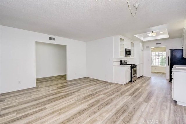 1919 Austin Ct, Claremont, CA 91711 - kitchen with stainless steel appliances, light wood finished floors, white cabinetry, a raised ceiling, and a textured ceiling