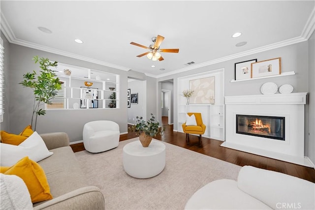 7626 Soaring Bird Ct, Eastvale, CA 92880 - living area featuring wood finished floors, ceiling fan, a fireplace with flush hearth, built in shelves, and ornamental molding