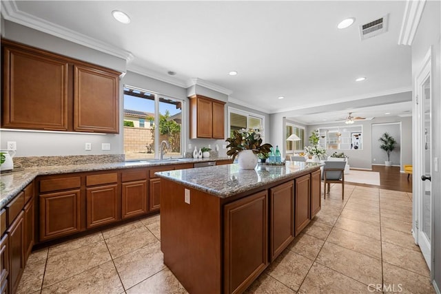 7626 Soaring Bird Ct, Eastvale, CA 92880 - kitchen with a center island, recessed lighting, a sink, brown cabinets, and light stone countertops