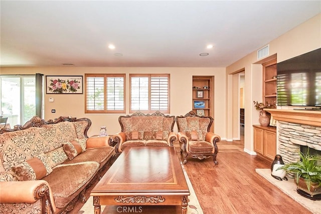 12430 Split Rein Dr, Rancho Cucamonga, CA 91739 - living area with light wood-style flooring, built in shelves, recessed lighting, and a stone fireplace