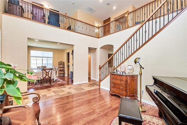 12430 Split Rein Dr, Rancho Cucamonga, CA 91739 - living area featuring arched walkways, wood finished floors, stairs, baseboards, and a high ceiling