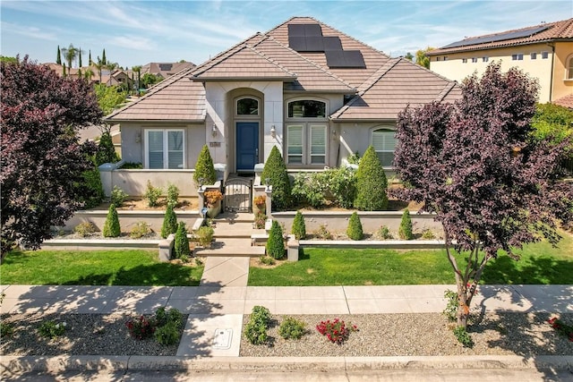 2096 E Olympic Ave, Fresno, CA 93730 - view of front of house featuring a tiled roof, stucco siding, roof mounted solar panels, and a gate