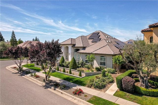 2096 E Olympic Ave, Fresno, CA 93730 - view of front of home featuring stucco siding, a tile roof, and roof mounted solar panels