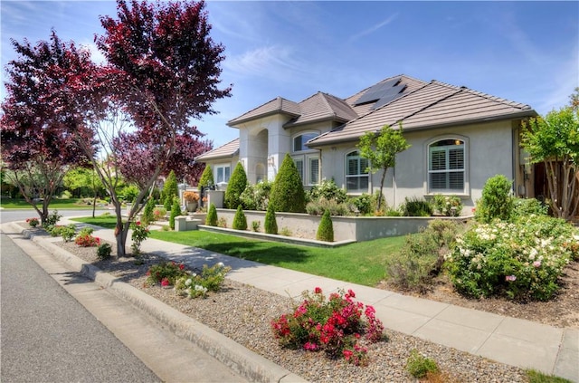 2096 E Olympic Ave, Fresno, CA 93730 - view of front of property with stucco siding, roof mounted solar panels, and a tiled roof