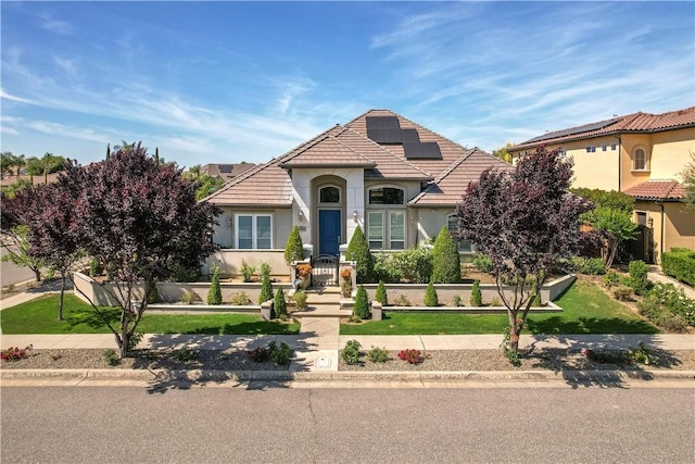 2096 E Olympic Ave, Fresno, CA 93730 - view of front facade featuring roof mounted solar panels, a tiled roof, and stucco siding