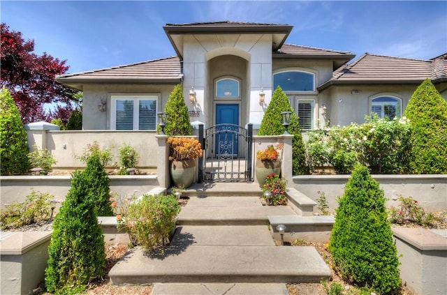2096 E Olympic Ave, Fresno, CA 93730 - mediterranean / spanish-style home featuring a gate, a tiled roof, stucco siding, and a fenced front yard