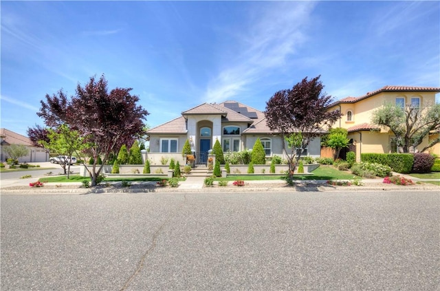 2096 E Olympic Ave, Fresno, CA 93730 - mediterranean / spanish-style home with solar panels, stucco siding, and a tile roof