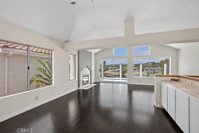 24851 Seagate Dr, Dana Point, CA 92629 - unfurnished living room featuring vaulted ceiling, a tile fireplace, dark wood-style floors, and baseboards