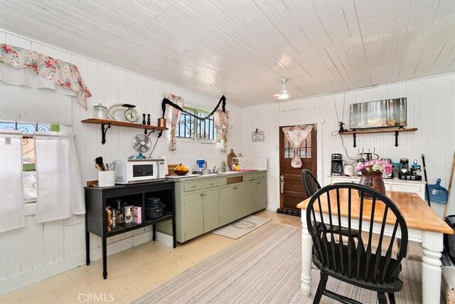 2368 E 107th St, Los Angeles, CA 90002 - kitchen with white microwave, green cabinetry, light floors, open shelves, and wood walls