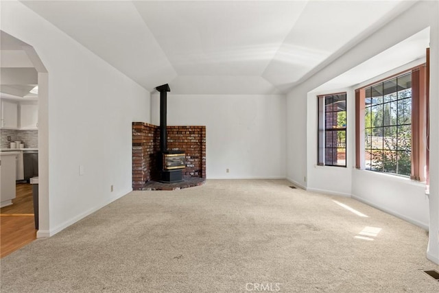 1585 Gate Ln, Paradise, CA 95969 - unfurnished living room with light colored carpet, a wood stove, lofted ceiling, arched walkways, and baseboards