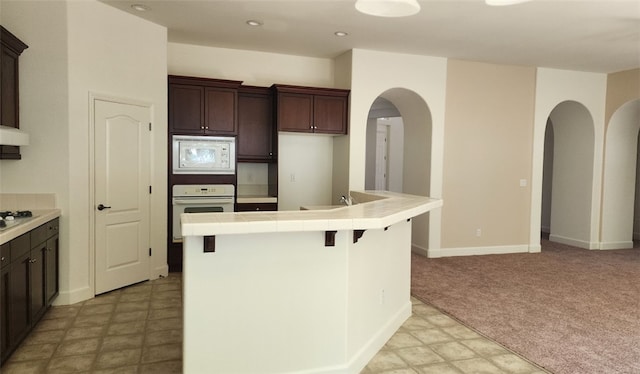 10372 Christo Way, Elk Grove, CA 95757 - kitchen with white appliances, dark brown cabinets, arched walkways, tile countertops, and light colored carpet