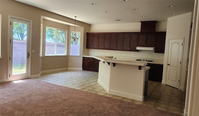 10372 Christo Way, Elk Grove, CA 95757 - kitchen with under cabinet range hood, a kitchen bar, tile counters, cooktop, and dark brown cabinetry